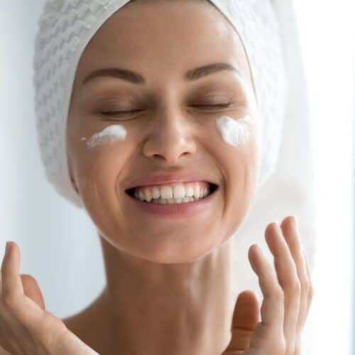 Woman smiling with moisturizer on her cheeks