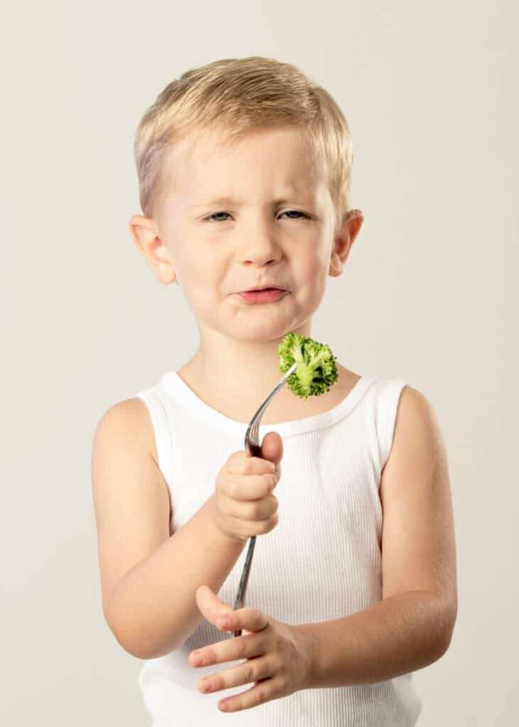 Boy looking at you disgusted with broccoli on fork