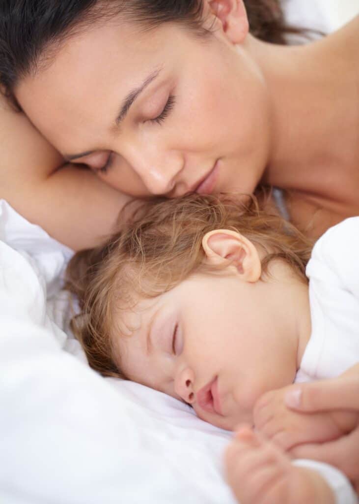 woman cuddling with sleeping toddler